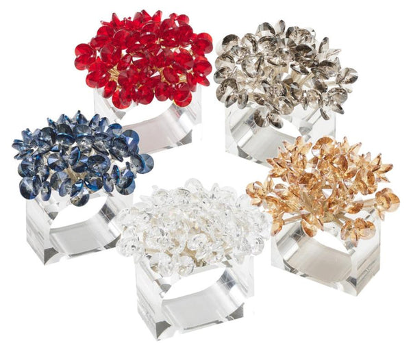 Five Kim Seybert Aster Napkin Rings, adorned with clusters in red, silver, gold, clear, and blue hues, each elegantly mounted on a transparent base. Perfect as table decor, these stunning pieces reflect light like dazzling glass beads from the renowned Kim Seybert brand.