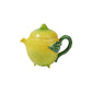 The Bordallo Pinheiro Lemon Collection teapot is shaped and painted like a lemon, with a green leaf handle and matching lid—an ideal charming addition to your citrus tableware. Displayed on a white background.