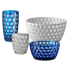 The Lente Acrylic Dinnerware Collection by Mario Luca Giusti features four glassware pieces—two bowls and two tumblers—in blue and clear with a raised bubble design, ideal for outdoor entertaining.