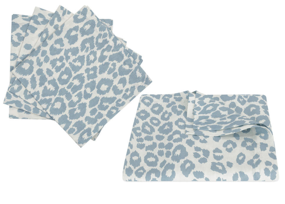 Six light blue and white leopard print cloth napkins from Matouk’s Iconic Leopard Sky Tabletop Collection, with four stacked on the left and two laid flat on the right.