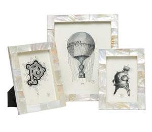 The Lesina Frame Collection by Pigeon & Poodle features three elegant white kabibe shell tile frames displaying black and white vintage illustrations—a letter P, hot air balloon, and diving helmet—to add coastal charm.