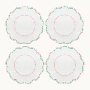 Four white, round, scalloped-edge plates with pink and green borders are arranged in a 2x2 grid, shown alongside the Duggan Society’s Lilibeth Table Linen Collection—perfect for your next gathering.