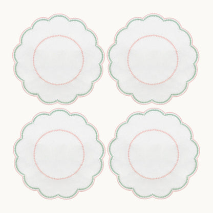 Four white, round, scalloped-edge plates with pink and green borders are arranged in a 2x2 grid, shown alongside the Duggan Society’s Lilibeth Table Linen Collection—perfect for your next gathering.