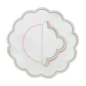 The Duggan Society Lilibeth Table Linen Collection features a round white scalloped embroidered placemat with green dots and pink trim, topped with a matching folded linen napkin—perfect for stylish table settings.