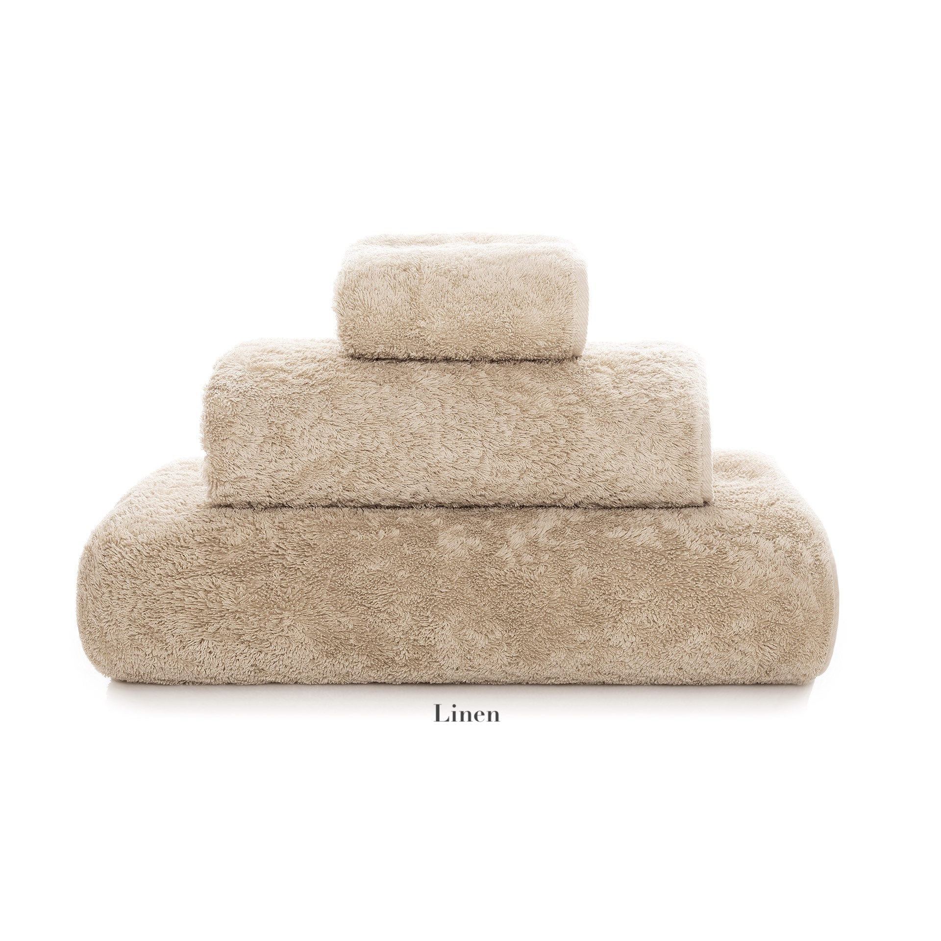 Three beige towels from the Egoist Bath Collection by Graccioza, in various sizes and made from high-density textile, are stacked in a pyramid shape on a white background.