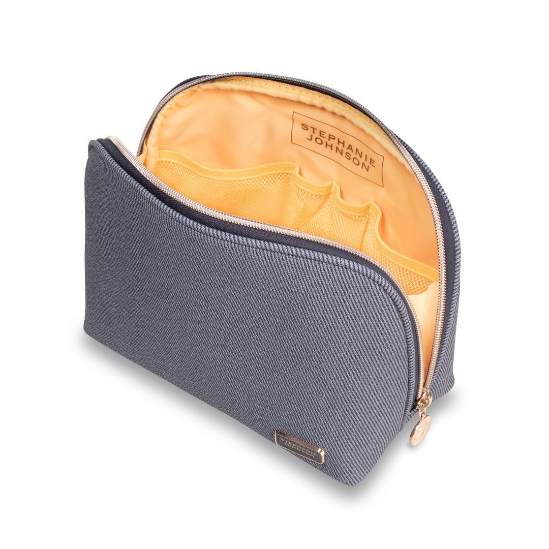 From the Stephanie Johnson Denim Travel Collection: a gray zippered makeup bag with yellow interior, multiple inner pockets, and a visible "STEPHANIE JOHNSON" label inside.