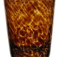 The Vanessa Tortoise Collection tumbler by William Yeoward Crystal features a mottled tortoiseshell design that creates an optical illusion on its smooth, brown glass cylindrical shape.