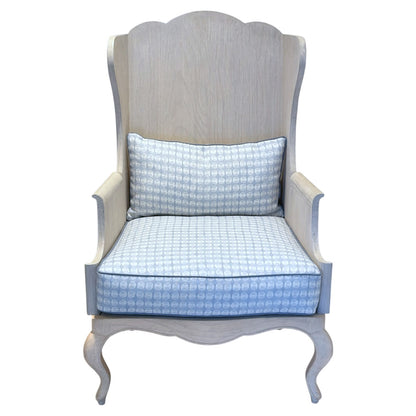 The Luberon Chair by Mr Brown features light wood, curved legs, a high back, and blue patterned cushions for French country flair, shown from the front against a white background.