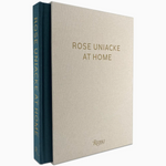 “Rose Uniacke At Home” by Rizzoli is a limited edition hardcover book that features a beige cover with gold lettering and a striking blue spine stamped with the title in gold. Inside, the renowned designer’s London home is depicted through captivating photography.