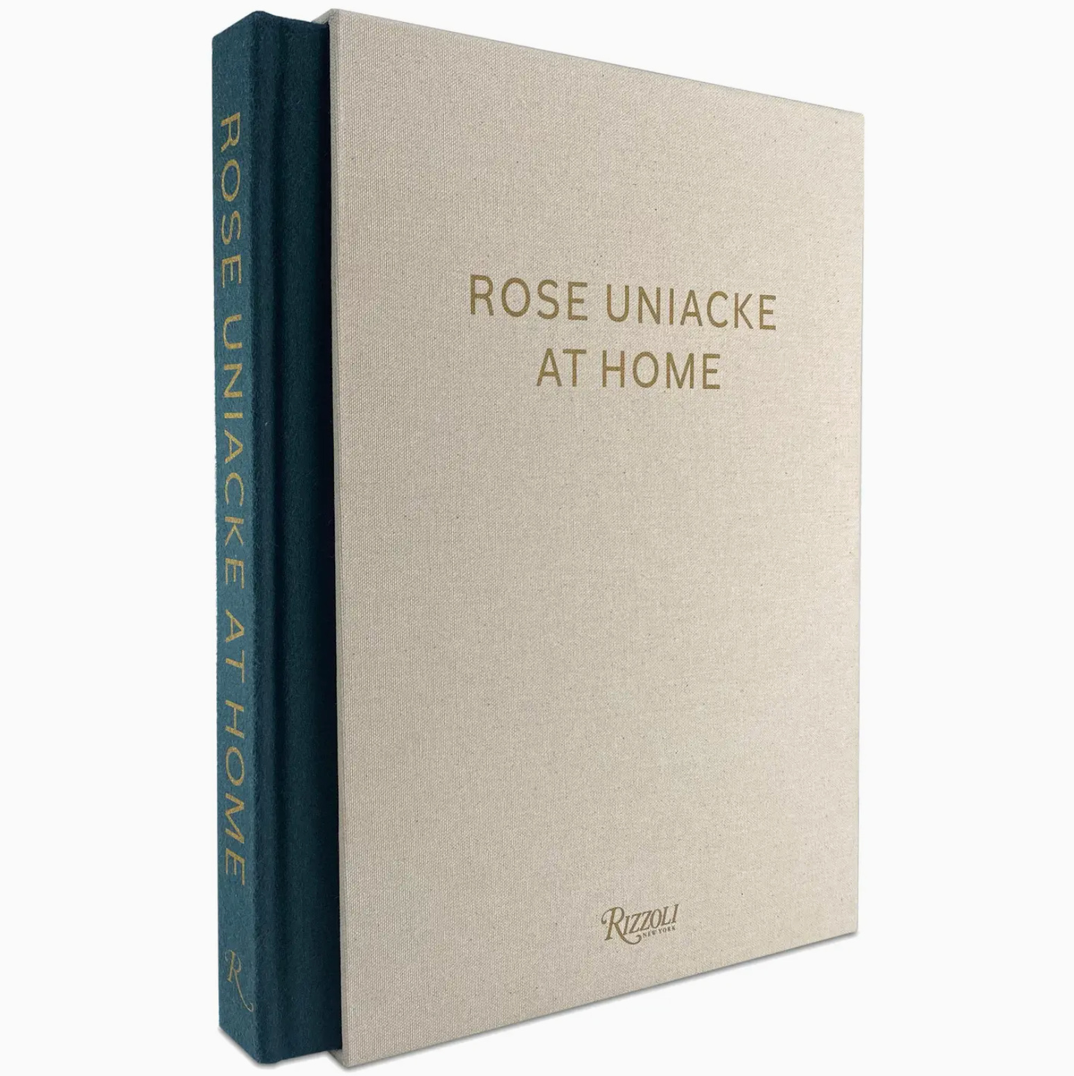 “Rose Uniacke At Home” by Rizzoli is a limited edition hardcover book that features a beige cover with gold lettering and a striking blue spine stamped with the title in gold. Inside, the renowned designer’s London home is depicted through captivating photography.