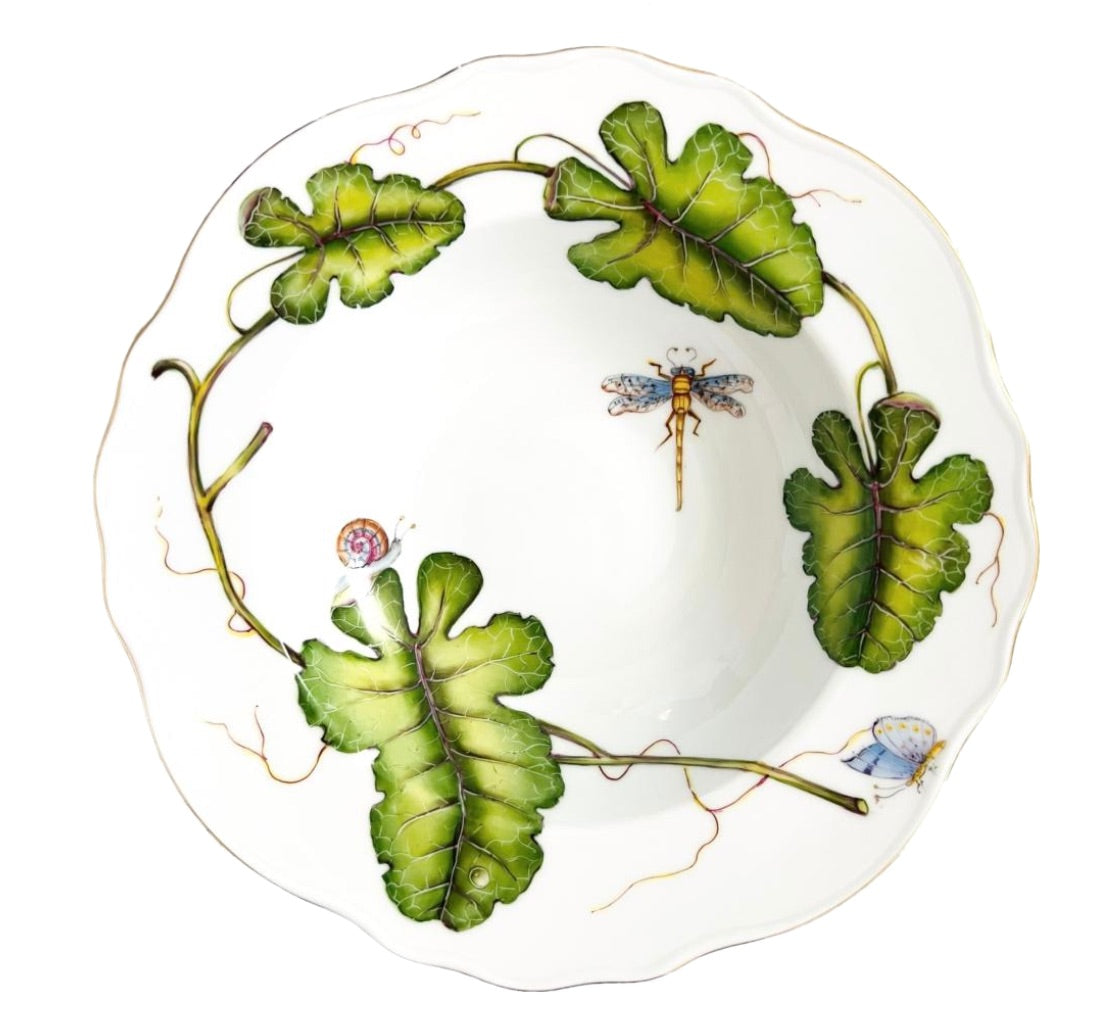 From the Garden Leaves Dinnerware Collection by Anna Weatherley, this white porcelain plate features a scalloped edge and is hand painted with green leaves, a dragonfly, a snail, and a butterfly, all elegantly connected by a vine motif.