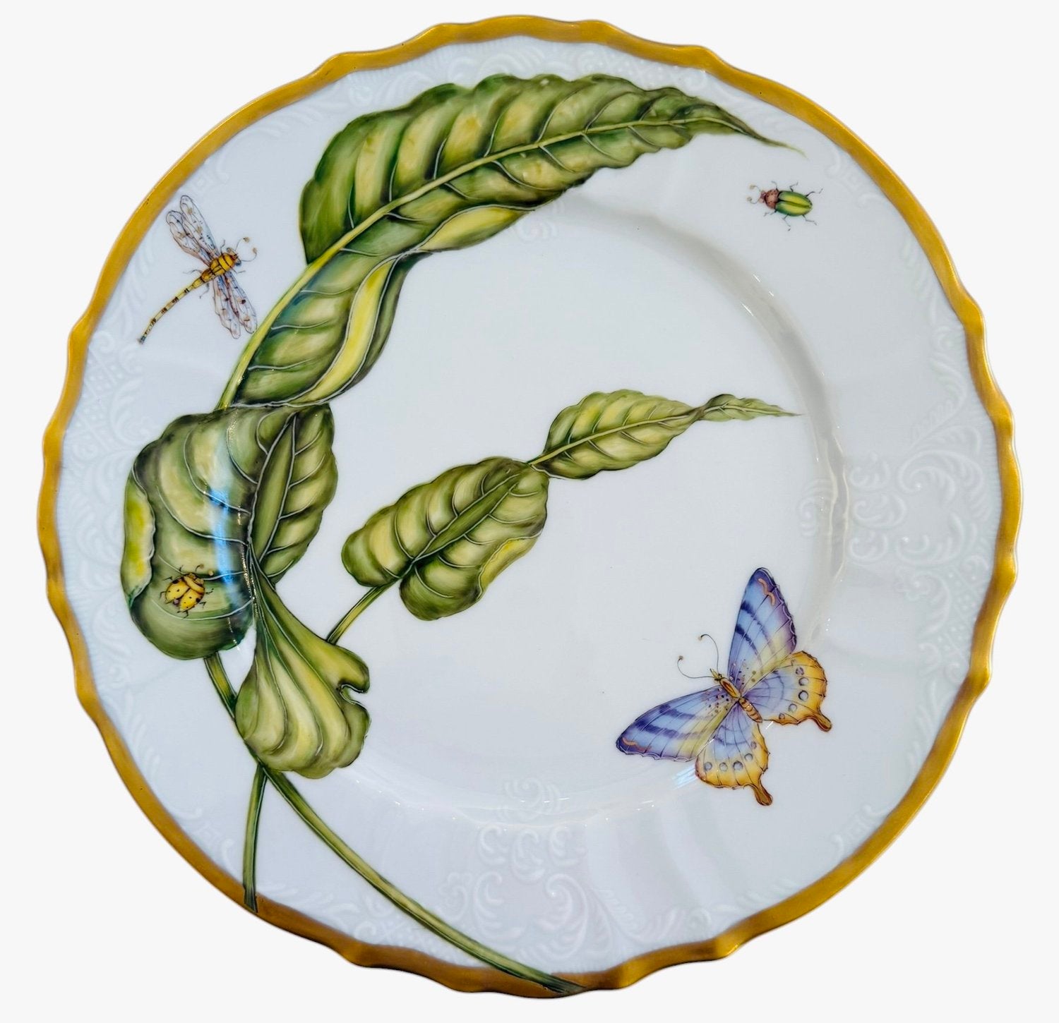 From the Elegant Foilage Dinner Plate Collection by Anna Weatherley, this decorative porcelain plate features hand-painted green leaves, a butterfly, dragonfly, and small insect, with a yellow scalloped rim and subtle white border pattern.