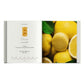 An open book from Simon & Schuster showcases a lemon macaron recipe on the left page, while the right page features a close-up image of fresh lemons alongside Ladurée Macarons, emphasizing their vibrant yellow shells and flavorful ganache filling.