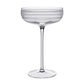 The Madison Drinkware Collection by William Yeoward Crystal features a clear coupe with a tall stem and horizontal frosted stripes, evoking Jazz Age elegance, shown here against a white background.
