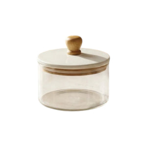 The Be Home Madras Canister is a clear glass jar with a round beige lid and wooden knob handle, ideal for kitchen storage and pantry organization. Photographed on a white background.