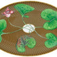 The Tresor Fleuri Marron Dinnerware Collection by Raynaud features an oval plate with a woven brown pattern, five hand-painted green leaves connected by stems, and a pink flower, radiating poetic porcelain charm.