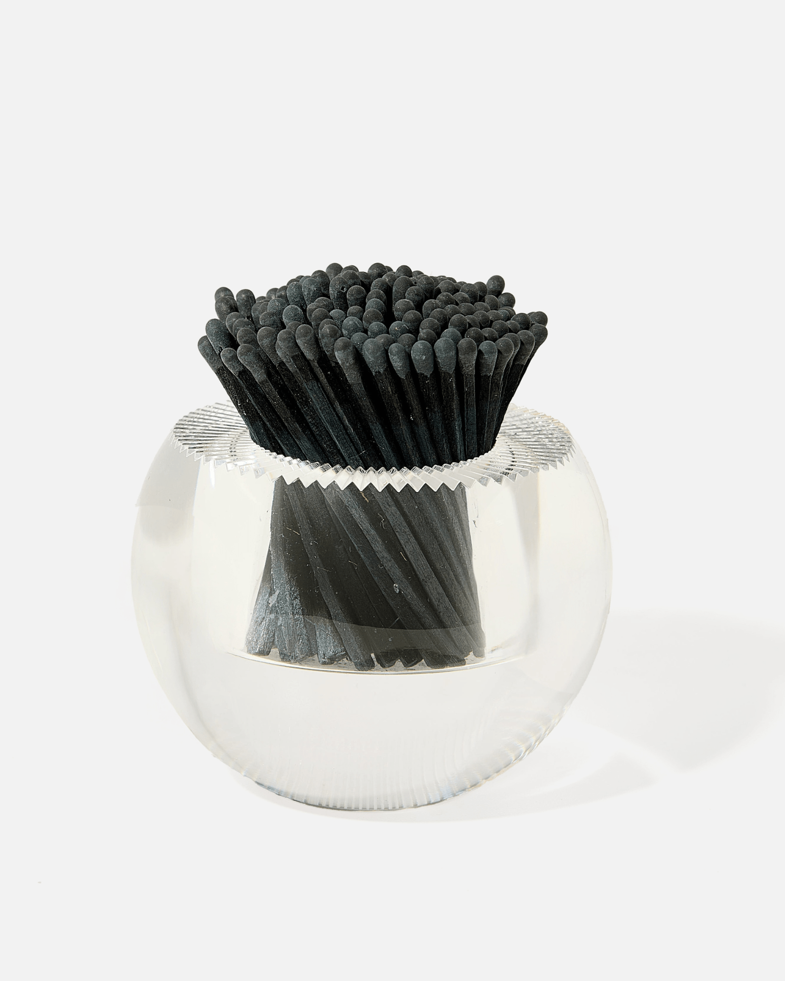 The Acrylic Match Striker Collection by Tart by Taylor features a clear acrylic holder filled with neatly arranged black-tipped, black-stemmed matches—an elegant accent for your coffee table.