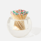 The Acrylic Match Striker Collection by Tart by Taylor features a clear round glass container filled with wooden matches tipped in pastel colors—a stylish, functional accessory perfect for your coffee table.