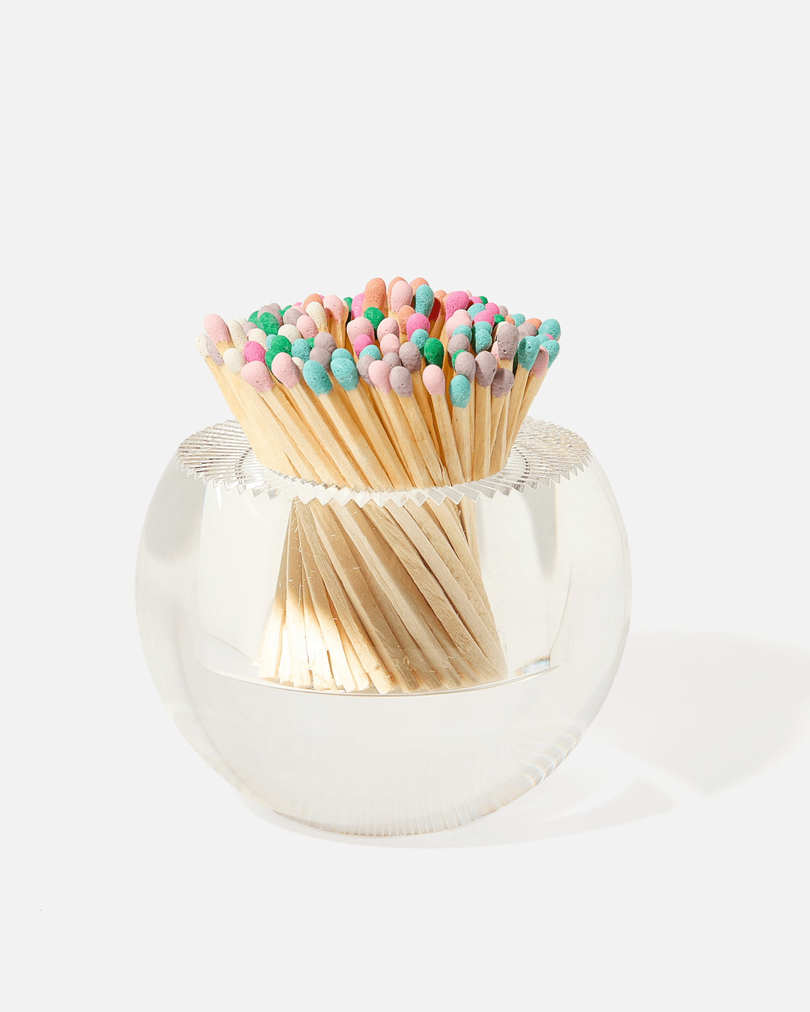 The Acrylic Match Striker Collection by Tart by Taylor features a clear round glass container filled with wooden matches tipped in pastel colors—a stylish, functional accessory perfect for your coffee table.