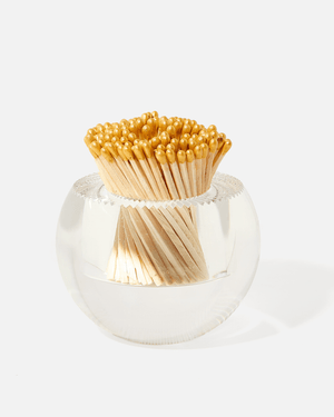 The Acrylic Match Striker Collection by Tart by Taylor features a clear glass container with yellow-tipped matches, arranged in a fan shape for a chic coffee table accent and functional match striker.