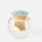 The Acrylic Match Striker Collection by Tart by Taylor holds a bundle of wooden matches with light blue tips, arranged heads up in a round glass container with an acrylic match strike—a stylish coffee table accessory.