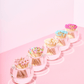 The Acrylic Match Striker Collection by Tart by Taylor features five round glass bowls with colorful-tipped wooden matches, lined up on a pink surface—ideal as a playful coffee table accessory and perfect for use with any acrylic match striker or strike pad.