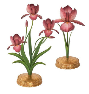 The Meadow Walk Iris Candle Holder Collection by Juliska features two hand-painted pink iris sculptures with green leaves on round gold-colored bases, accented with Berry & Thread motifs, elegantly displayed against a white background.