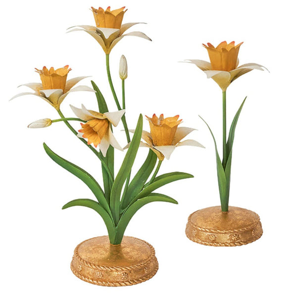 Two metal sculptures of orange and white flowers with green stems on golden bases capture the charm of the Juliska Meadow Walk Daffodil Candle Holder Collection, adding elegance to any setting.