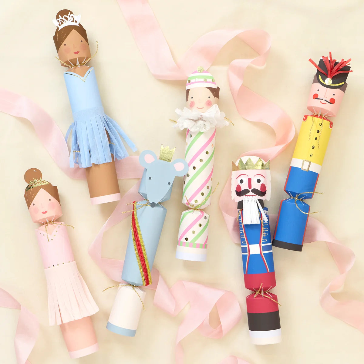 Six Nutcracker Ballet Crackers by Meri Meri shaped as ballerinas, a mouse, and soldiers, arranged as festive table favors on a light background with pink ribbon.