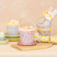 MERI x Liberty Paper Baskets by Meri Meri, filled with eggs and flowers, are displayed on plates and a wooden board against a neutral background.