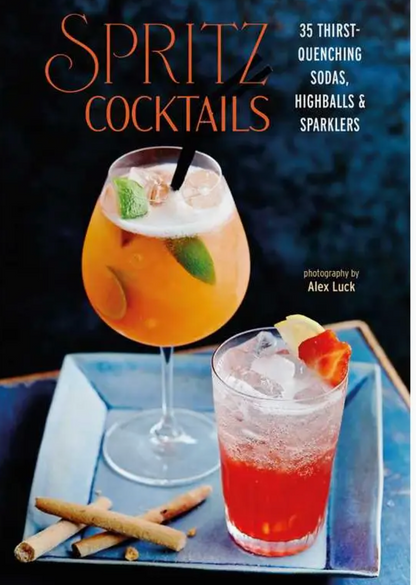 Cover of the Simon & Schuster book “Spritz Cocktails,” showcasing two spritz cocktails crafted with sparkling wine and Italian amaro, garnished and accompanied by cinnamon sticks and a blue napkin on a table.