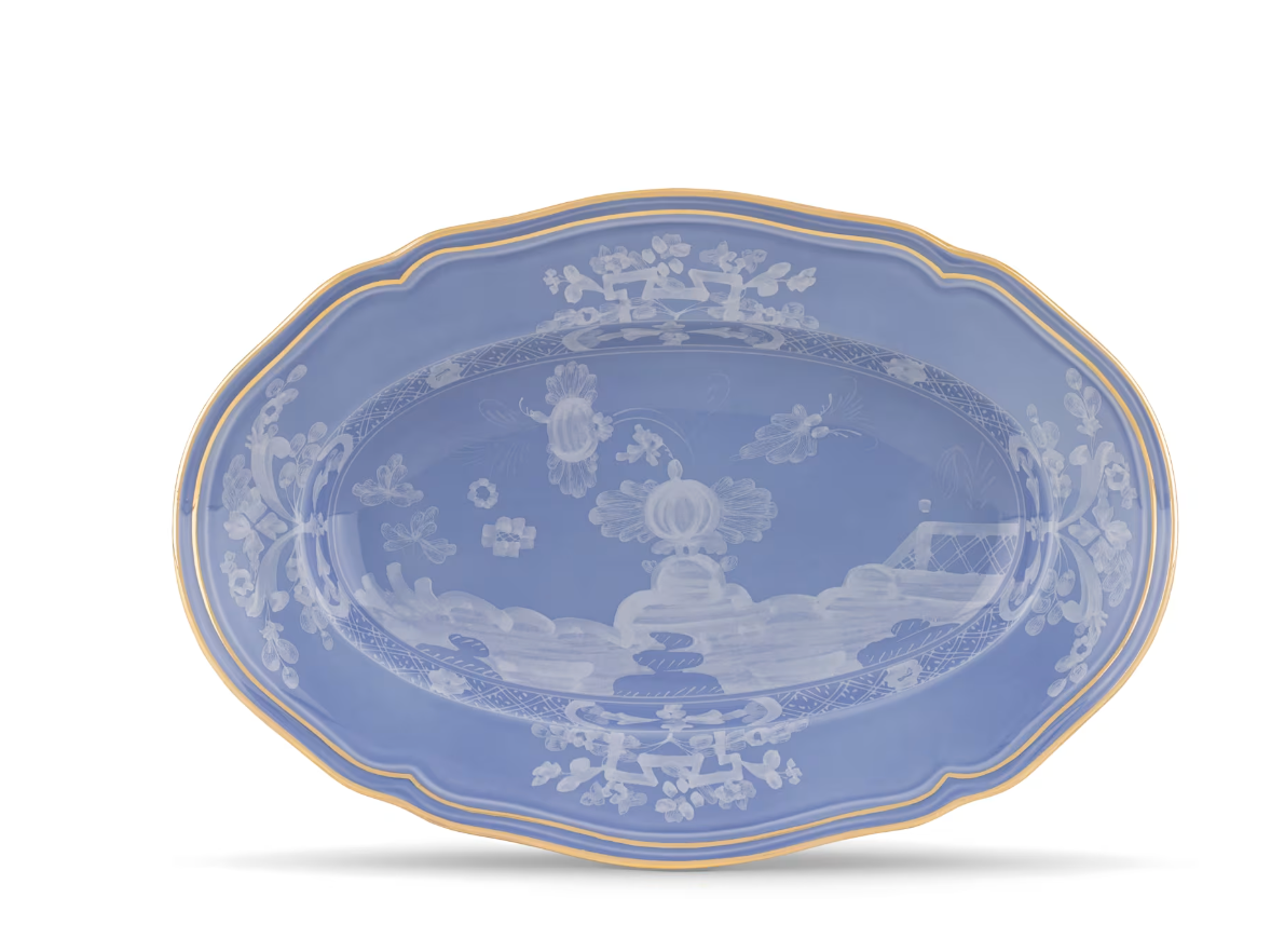 A blue oval porcelain platter from the Oriente Italiano Pervinca Serveware & Decor Collection by Ginori 1735, featuring a gold rim and delicate white floral patterns inspired by classic Oriente Italiano designs, displayed against a white background.