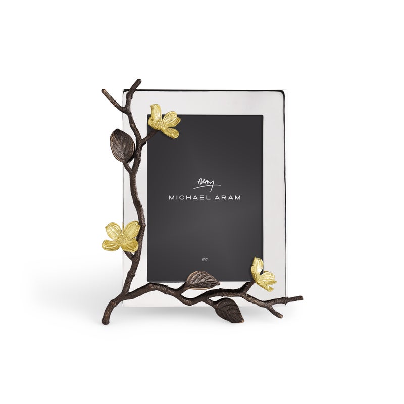 The Michael Aram Dogwood Frame is a handcrafted goldtone photo frame featuring a decorative metal branch with gold flowers on the left and a placeholder displaying “Michael Aram.”.
