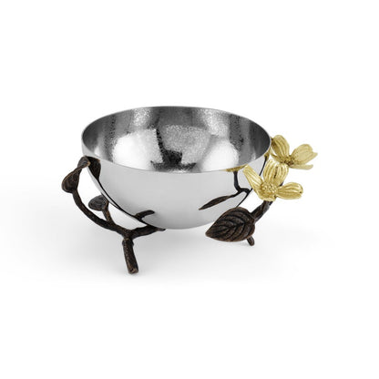 A shiny silver bowl rests in a decorative stand with branch-like supports, bronze leaves, and gold-toned flowers—showcasing the nature-inspired Dogwood Serveware Collection by Michael Aram.