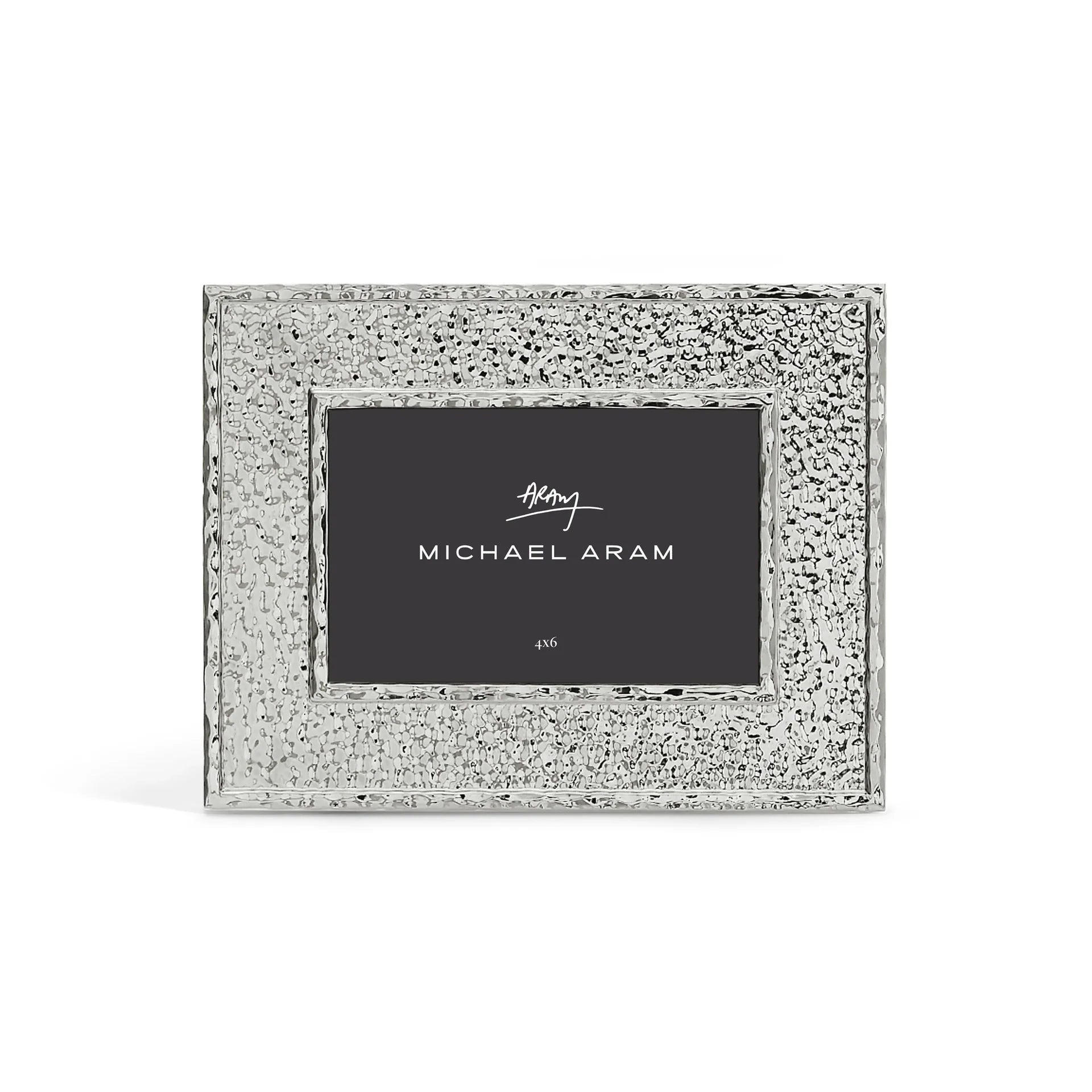 The Hammertone Frame by Michael Aram is a silver, textured rectangular photo frame featuring a refined hammertone metal finish and a black inner label displaying the “Michael Aram” signature in white text, designed to hold a 4x6 photo.