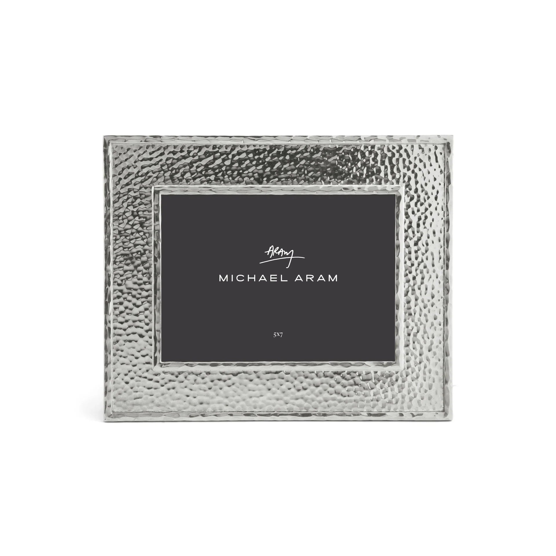 The Michael Aram Hammertone Frame is a square picture frame crafted from hammered metal, showcasing a distinctive hammertone texture and featuring a dark insert with “Michael Aram” printed in white at the center.