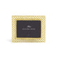 The Michael Aram Love Knot Gold Frame Collection features a gold lattice photo frame with a black card at the center, inspired by the Love Knot motif to symbolize unity and connection.
