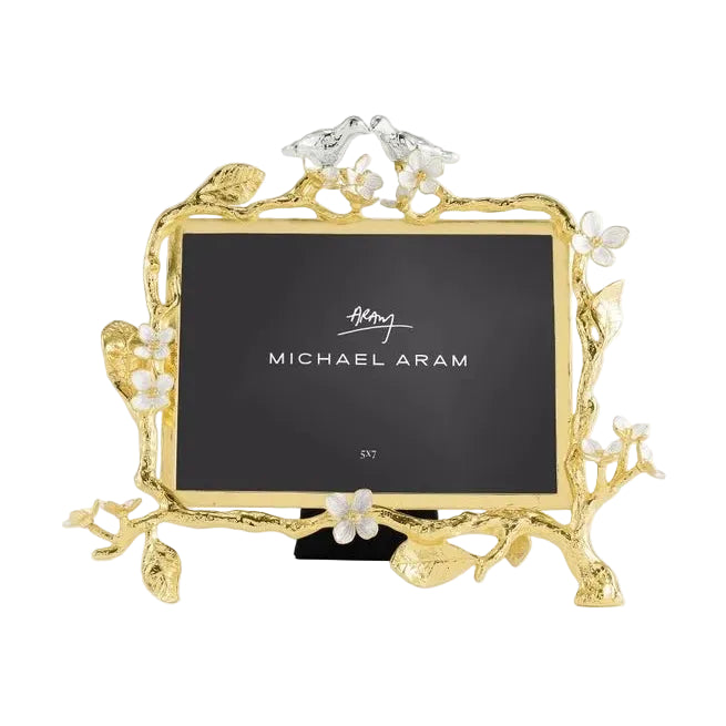 The Lovebirds Frame Collection by Michael Aram features a gold and silver picture frame adorned with floral and branch motifs, topped with two charming birds and finished with a black insert—making it an ideal choice for an elegant wedding or timeless anniversary gift.