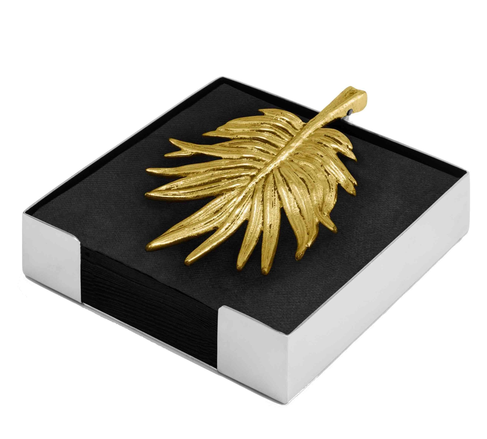 A gold leaf-shaped piece with sculpted textures sits on black napkins in a white square holder, showcasing the Palm Serveware Collection by Michael Aram.