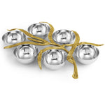 Six round silver bowls from Michael Aram’s Palm Serveware Collection are arranged with sculpted, antique gold-toned branches intertwined on top.
