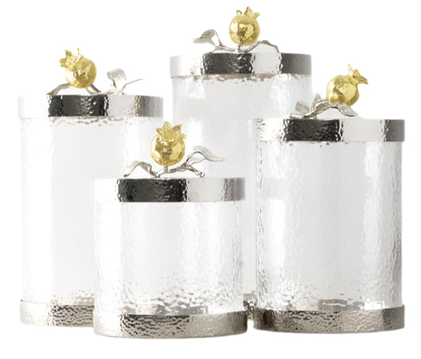 The Michael Aram Pomegranate Silver & Gold Canisters feature four silver and glass containers with lids, adorned with gold pomegranates and leaves, reflecting the timeless beauty of Michael Aram's designs. These motifs honor ancient symbols of fertility and union.