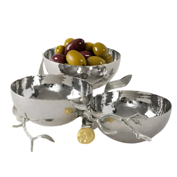 Three silver bowls from Michael Aram’s Pomegranate Silver & Gold Serveware Collection, joined by decorative branches and one holding green and purple olives, crafted in stainless steel nickelplate and goldplate on a white background.