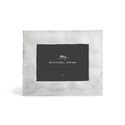 The Reflective Frame Nickel Collection by Michael Aram features a square metallic design with a nickelplate finish, black center insert displaying the brand name in white, all set against a plain white background for a modern look.