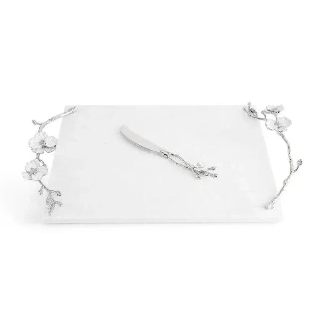 With its rectangular white marble base, silver branch handles, and coordinating silver knife resting on top, the Michael Aram Silver Orchid Collection serving tray evokes purity and grace reminiscent of the elegant orchid plant.