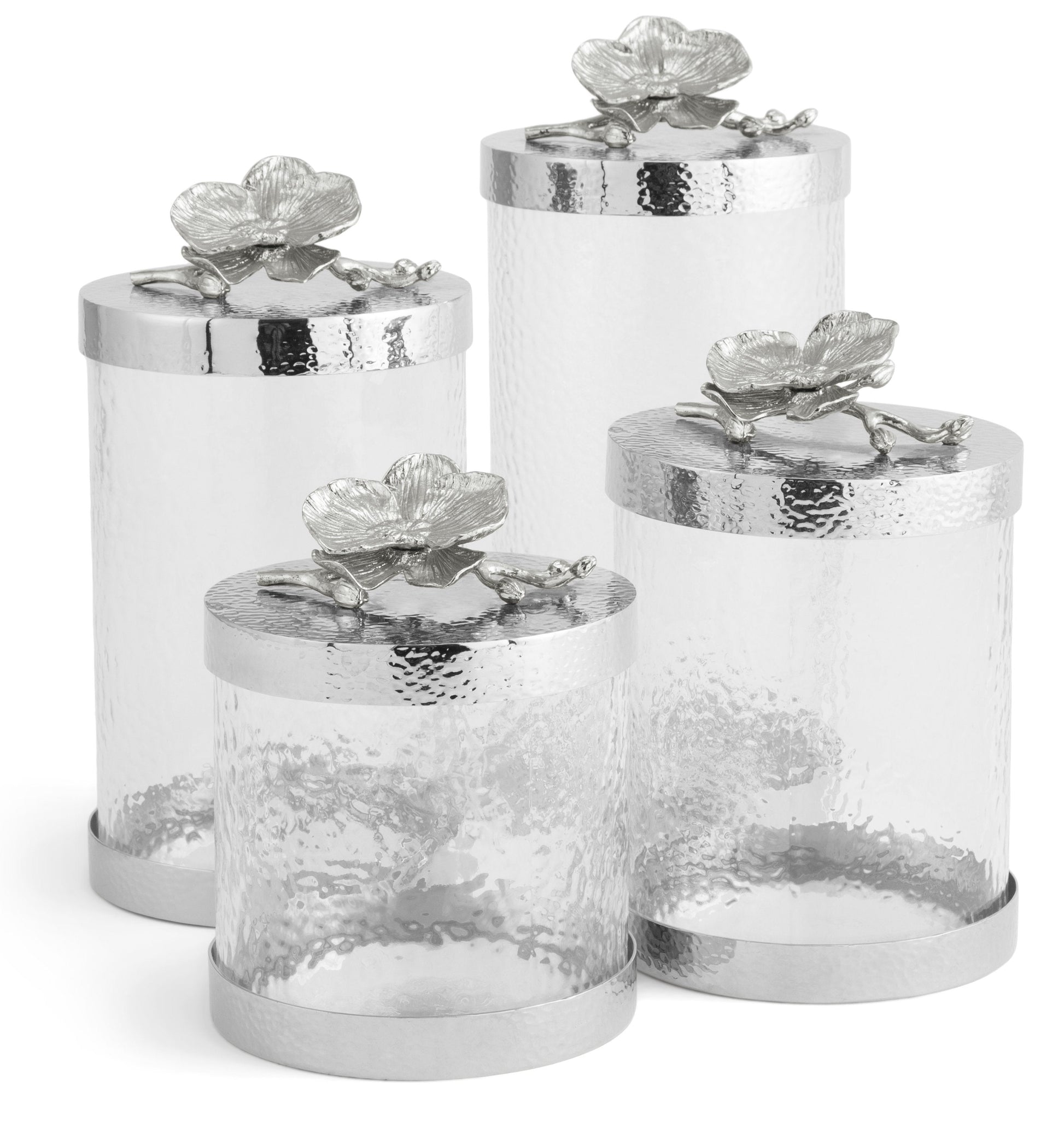 The Michael Aram White Orchid Canister Collection features elegant glass containers adorned with floral accents, highlighting exquisite luxury craftsmanship.