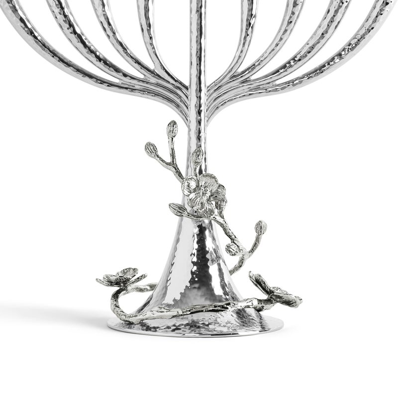 Close-up of the base of the Michael Aram White Orchid Menorah, featuring a hammered texture and adorned with detailed flower and branch motifs.