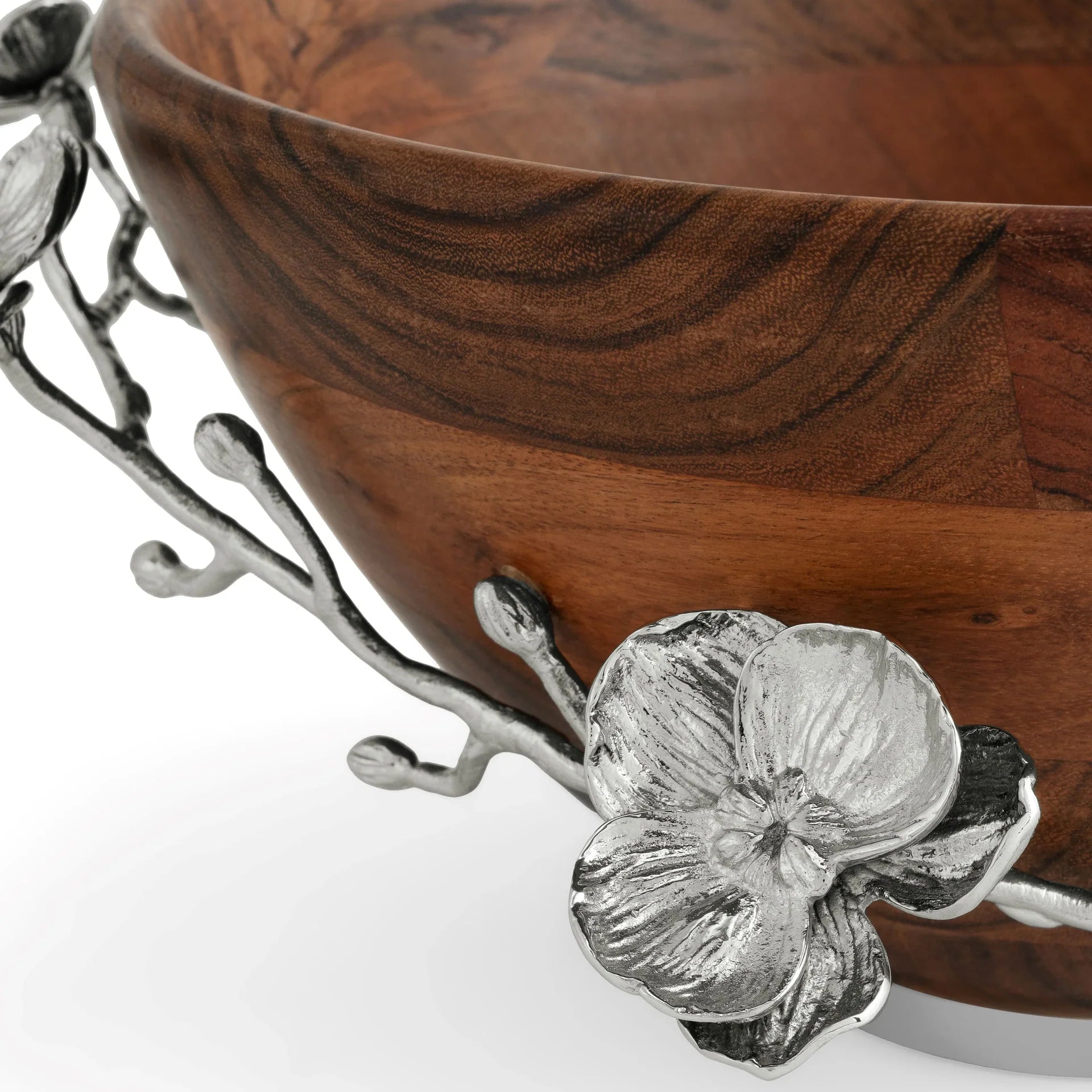 A close-up of the Michael Aram White Orchid Wood Salad Bowl showcases its rim adorned with intricate silver enamel floral and branch decorations, featuring detailed blooms and leaves.