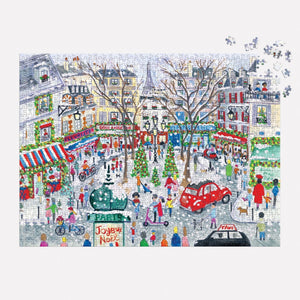 The 1000 Piece Puzzle by Michael Storrings, titled "Christmas in Paris" and produced by Chronicle Books, presents a vibrant illustration of a bustling Parisian street during Christmas. It depicts people wandering among adorned trees and iconic buildings, with an intriguing twist as some pieces are absent in the top right corner.