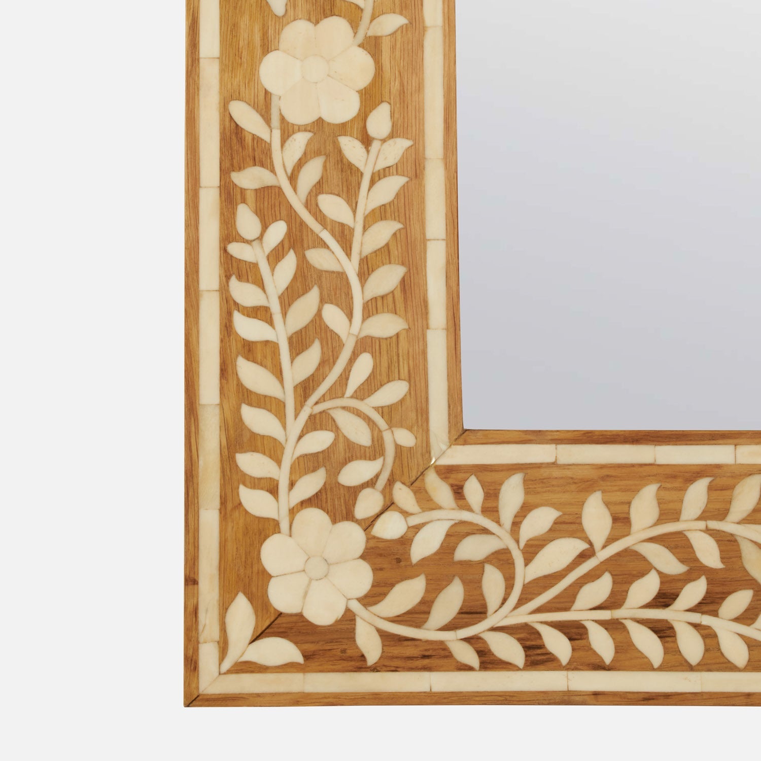Close-up of the Adelise Oak & Bone Mirror by Made Goods, showcasing inlaid floral and leaf patterns in light material on its frame.