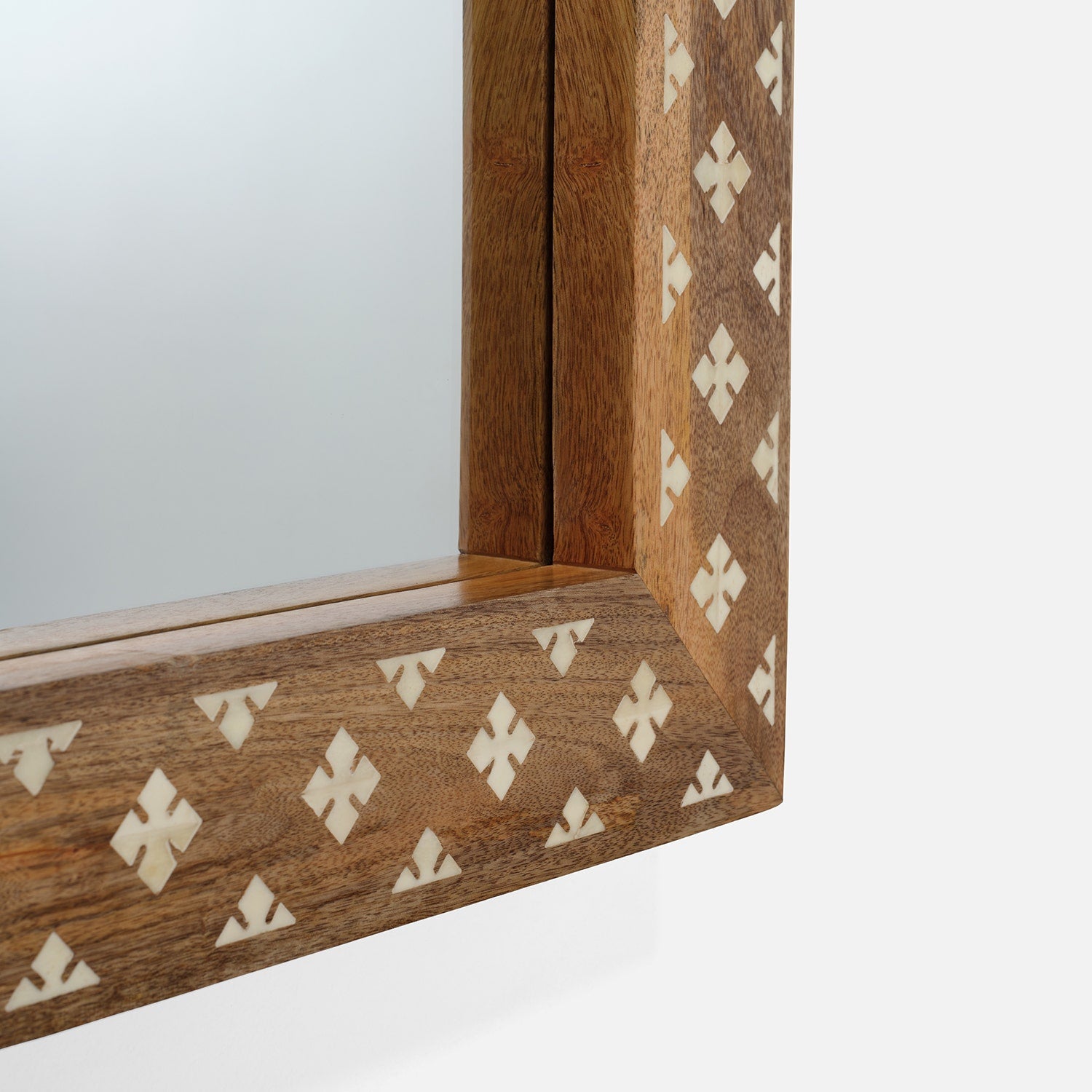 Close-up of the Izan Rectangular Mirror by Made Goods, featuring a wooden frame with a diamond and cross inlay pattern in contrasting light and dark wood tones.